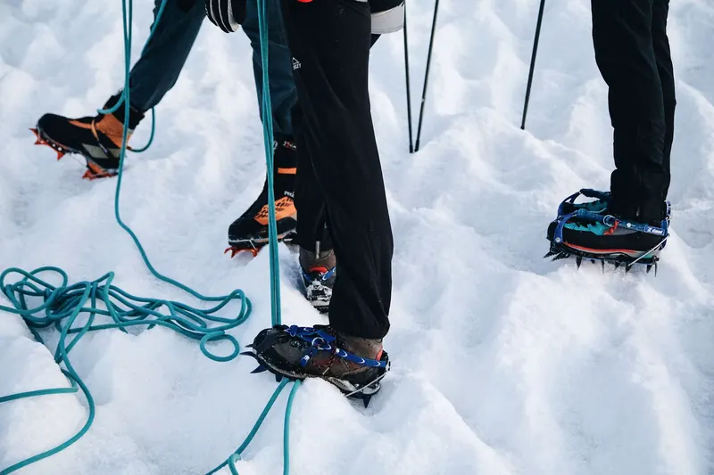 Adventurers with crampons and ropes preparing for a snowy mountain climb