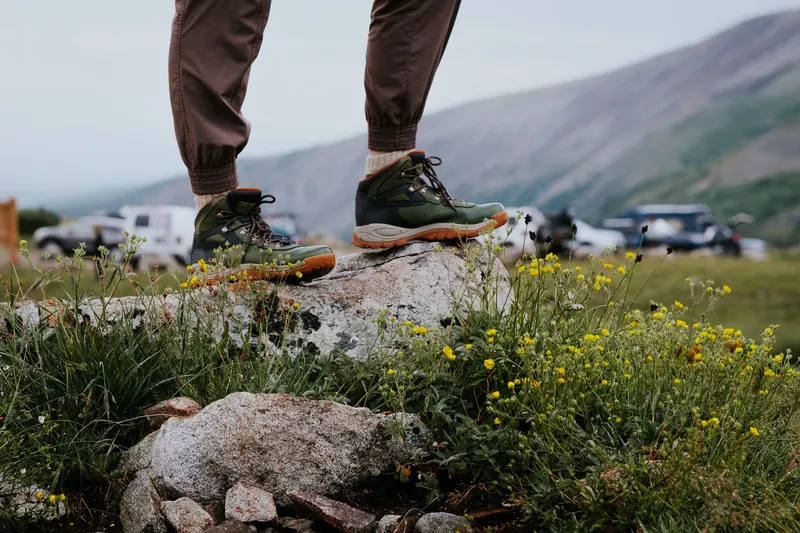 Close-up of hiking boots on a rocky outcrop surrounded by wildflowers in Alma, Colorado