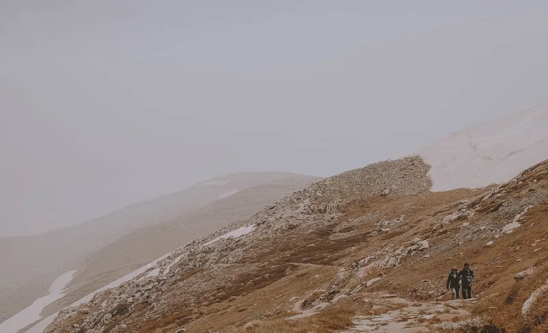Two hikers walking on a rocky mountain path in Kosciuszko National Park, NSW, Australia
