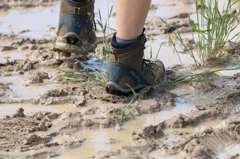 Close-up of hiking boots walking through muddy terrain in South Dakota, capturing adventure and exploration
