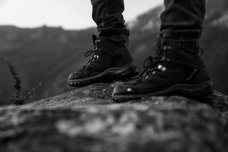 Close-up of hiking boots standing on a rock, showcasing outdoor adventure style in monochrome