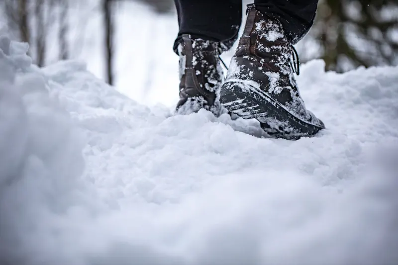 Close-up of boots stepping in deep snow, showcasing winter footwear in a snowy landscape